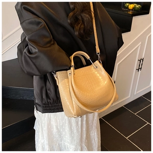Detail of beige crocodile pattern bucket bag with silver hardware and adjustable strap