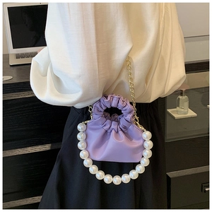 Close-up of lavender pleated cloud bag with large pearl handle and gold chain strap