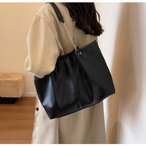 Detailansicht schwarze Tragetasche aus mattem Leder mit Steppnähten und goldener Kette