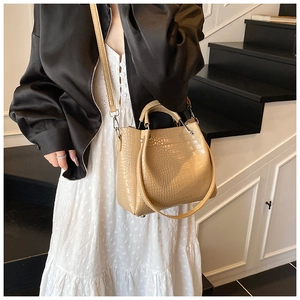 Detail of beige crocodile pattern bucket bag with silver hardware and detachable strap