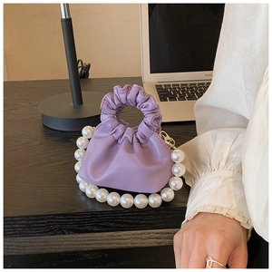 Close-up of light purple pleated cloud bag featuring a decorative large pearl top handle