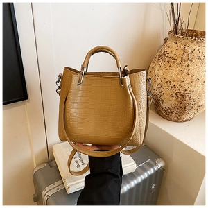 Detail of crocodile embossed camel handbag with metallic hardware in a stylish travel setting
