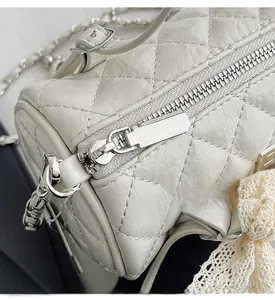Detail shot of the smooth silver zipper and quilted leather on the white cylinder bag