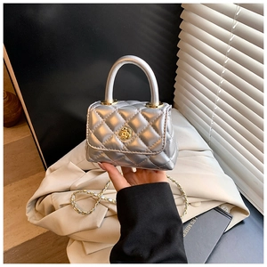 Close-up of a silver quilted mini bag with a golden rose clasp and chain strap detail
