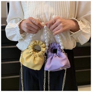 Detail of yellow and purple pleated cloud bags with large pearl handle and gold chain strap
