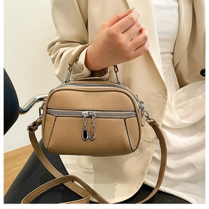 Detail of khaki faux leather handbag with lychee texture and decorative dual zippers