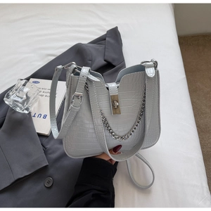 Detail der hellblauen Handtasche mit Krokodilstruktur, Silberverschluss und Kette