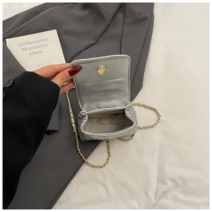Detail of silver quilted mini bag featuring magnetic closure and metallic chain strap