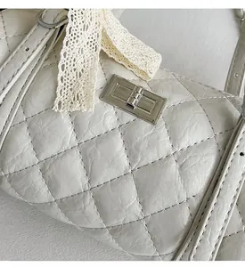 Detail of cream quilted cylinder bag with lace ribbon and silver rectangular twist lock
