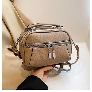 Detail of khaki faux leather crossbody bag with triple zipper layers and lychee texture
