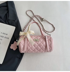 Close-up of pink quilted barrel bag with lace bow and adjustable silver chain strap