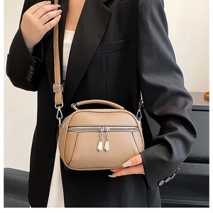 Detail of khaki pebbled leather shoulder bag with double zipper and silver hardware