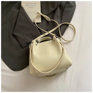Detail of cream crocodile embossed bucket bag with silver metal feet and sturdy top handle