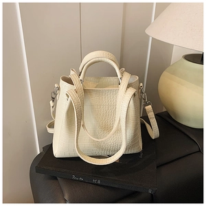 Detail of cream crocodile embossed leather handbag with silver hardware and top handles