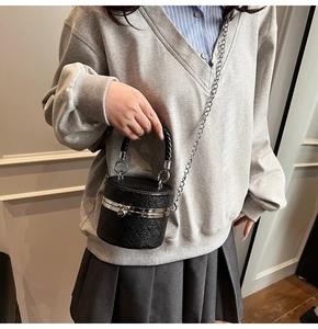 Details der schwarzen gesteppten Zylindertasche mit Silberkette und Tragegriff