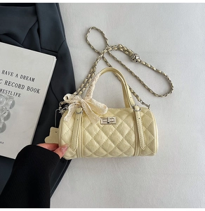 Detail of quilted barrel bag with silver turn-lock closure and lace bow accessory