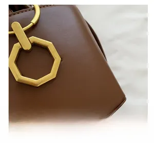 Gros plan détaillé d'un sac seau en cuir marron foncé avec boucle octogonale dorée
