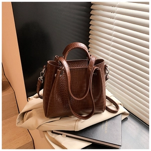 Close-up of deep brown crocodile pattern leather tote with top handle and natural lighting