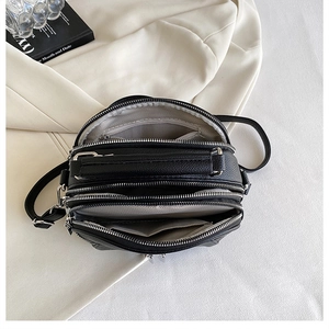 Detail view of multi-layer zipper compartments and pebble leather texture on a crossbody bag