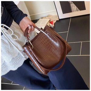 Detail of deep brown crocodile pattern bucket bag with silver hardware and handle