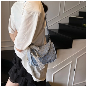 Detail of blue denim shoulder bag with silver studs, lace bow and pearl chain decoration