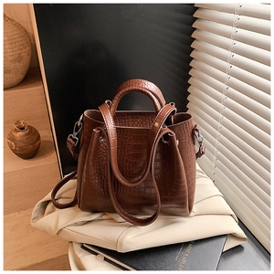 Close-up of deep brown crocodile embossed leather handbag on elegant fabric background