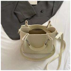Detail of a creamy white crocodile pattern bucket bag with interior pocket and straps