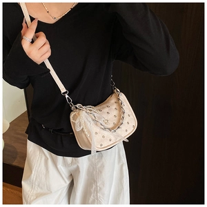 Detail of beige rivet handbag with silver chain, pearl strap and lace decoration