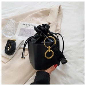 Détail du sac seau noir à cordon avec une poignée dorée unique et une texture en cuir
