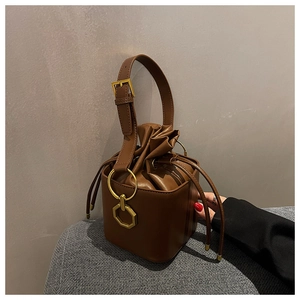 Détail du sac seau vintage en cuir marron avec anneaux dorés et fermeture à cordon