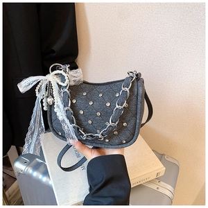 Detail of dark denim handbag with silver rhinestones, metal chain and lace bow charm
