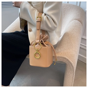 Détail du sac seau crème avec texture litchi et boucle métallique dorée géométrique