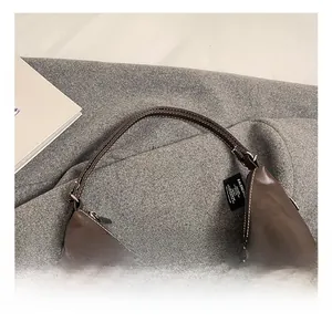 Close-up of brown leather handbag featuring white stitching and silver metal buckle detail