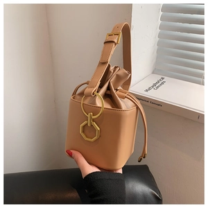 Détail du sac seau marron clair avec cordon et garnitures dorées en forme d'anneau