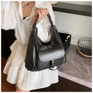 Detail of black PU leather shoulder bag featuring white contrast stitching and front pocket