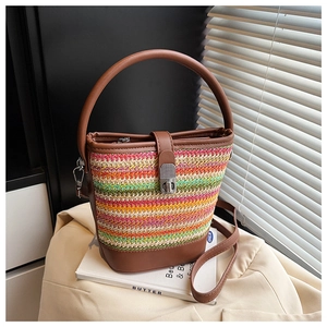 Detail of colorful woven bucket bag with brown leather base and silver turn-lock closure