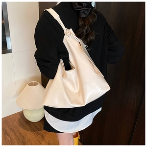 Minimalist beige PU leather hobo tote bag shown worn on shoulder in a cozy indoor setting