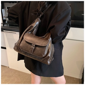 Detail of dark brown large capacity crossbody bag with contrast stitching and front pocket