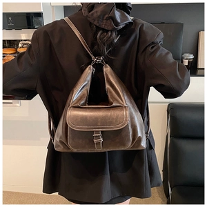 Close-up of vintage brown leather backpack with white stitching and flap closure