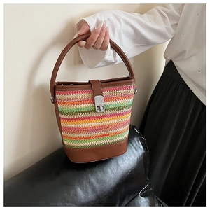 Detail of colorful woven bucket bag featuring striped raffia and leather twist lock