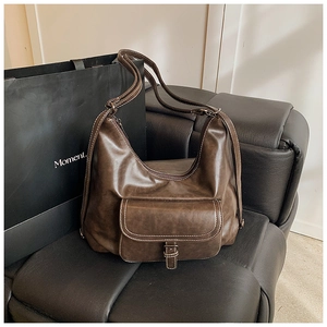 Detail of vintage dark brown faux leather bag with white stitching and buckled pocket