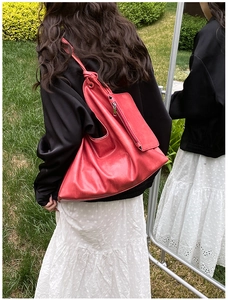 Detailed view of red PU leather tote bag with side pouch shown on model outdoors