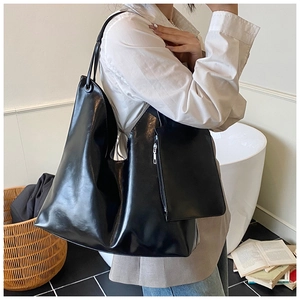 Large black glossy tote bag with detachable pouch shown in a stylish commute setting