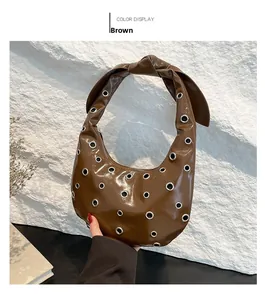 Detail of glossy brown patent leather tote featuring metal eyelets and knotted strap handle