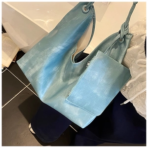 Macro shot of lake blue PU leather tote bag with matching zippered pouch on white tiles