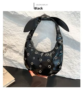 Detail of black glossy saddle bag featuring silver eyelets and a stylish bow strap
