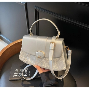 Close-up of metallic silver handbag featuring snake pattern embossing and M-logo buckle