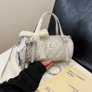 Beige quilted cylinder Boston bag with lace bow and metal chain strap for women