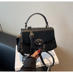 Detail of black crossbody bag with snake texture trim and metallic M logo buckle