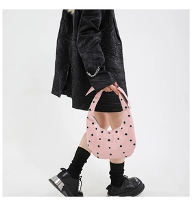 Detail of pink crescent bag with polished finish and metallic rivet eyelets decoration